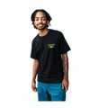 A man wearing a black Volcom Stone t-shirt with a gold logo on the left chest, paired with teal pants, isolated on a white background.