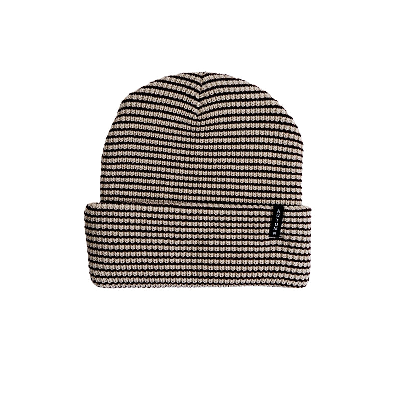 A black and beige patterned knit beanie hat with a folded cuff, shown against a plain white background.