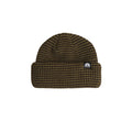 A ribbed knit beanie hat in a dark brown and black micro-check pattern, featuring a small white embroidered logo patch on the front cuff.