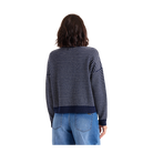 A person shown from the back wearing a navy and white horizontally striped knit sweater with blue jeans, isolated on a solid black background.