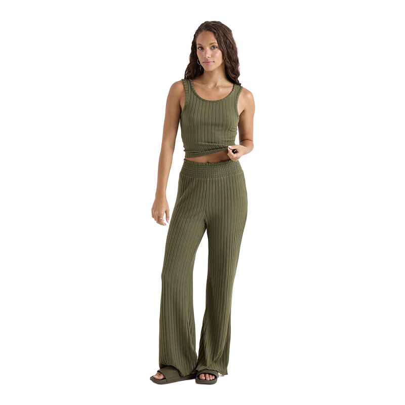 A woman modeling a matching ribbed knit two-piece set consisting of a cropped tank top and wide-leg pants in olive green, shown against a plain white background.