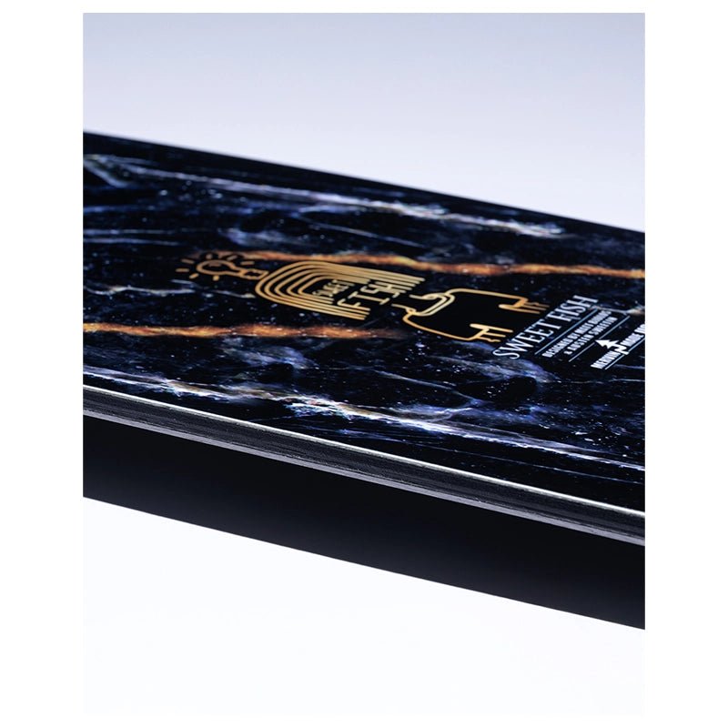 A close-up angled view of a rectangular product with a black marble pattern, featuring gold and white text and graphics, including the brand name 'SWEET TART'.