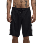 Black men's swim trunks with a white graphic print down the sides, modeled on a man's lower torso against a white background.