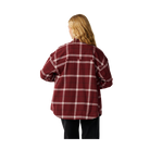 A woman viewed from behind wearing an oversized red and white plaid flannel shirt and black pants, isolated on a solid white background.