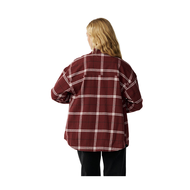 A woman viewed from behind wearing an oversized red and white plaid flannel shirt and black pants, isolated on a solid white background.