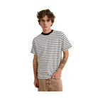 A young man with curly brown hair wearing a black and white horizontally striped t-shirt with a black crew neck, paired with beige pants, standing against a neutral beige background.