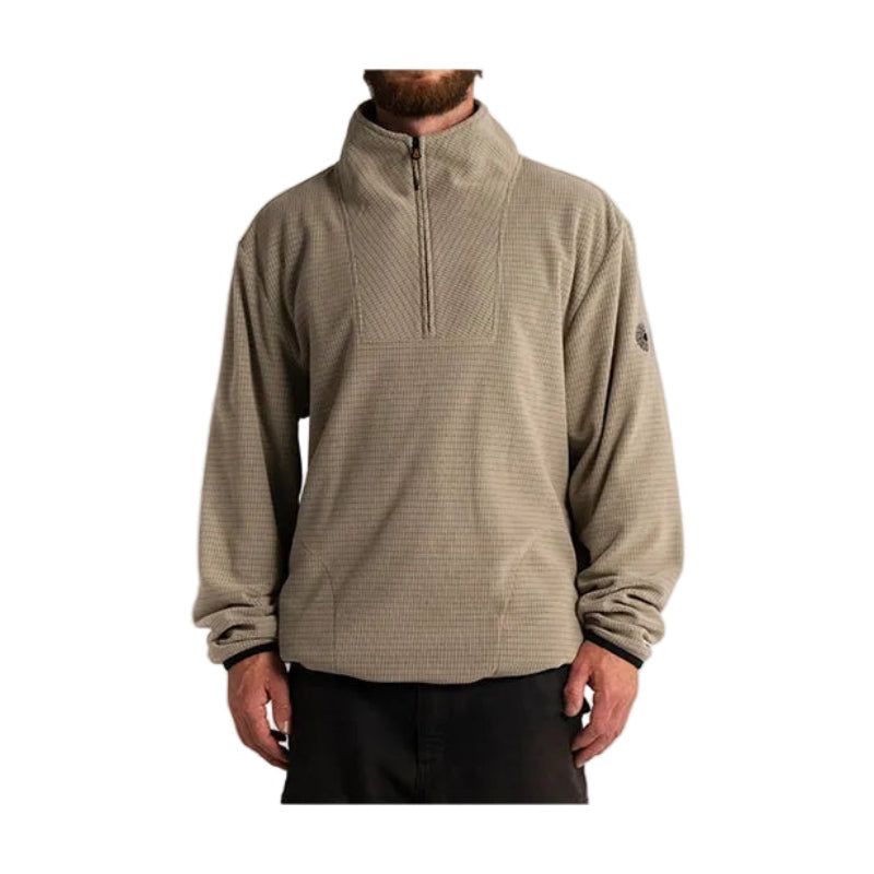A man wearing a beige textured quarter-zip fleece pullover with black pants, shown from the chin down against a light gray background.