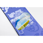 A 14.9 cm skateboard deck by Iris Flowers, featuring a blue-purple background with white butterfly and floral line art, and a central graphic of hands holding flowers over a landscape with a rainbow.