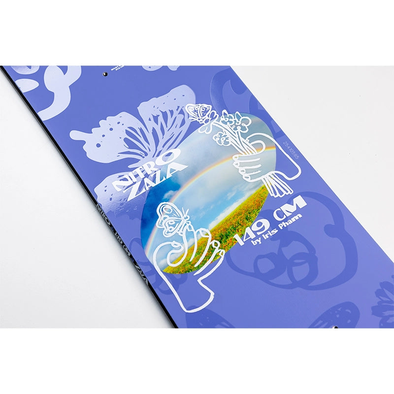 A 14.9 cm skateboard deck by Iris Flowers, featuring a blue-purple background with white butterfly and floral line art, and a central graphic of hands holding flowers over a landscape with a rainbow.