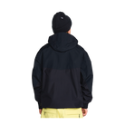 A person shown from the back wearing a dark navy hooded jacket, a black knit beanie, and light yellow pants against a plain white background.